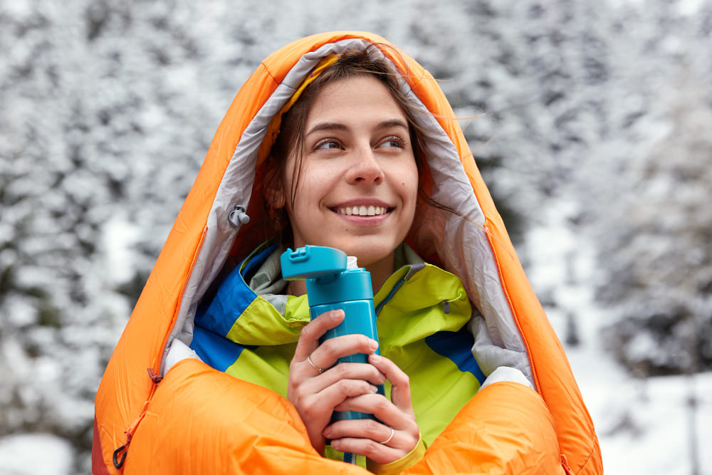 mujer en la nieve que está haciendo una hidratación en la nieve